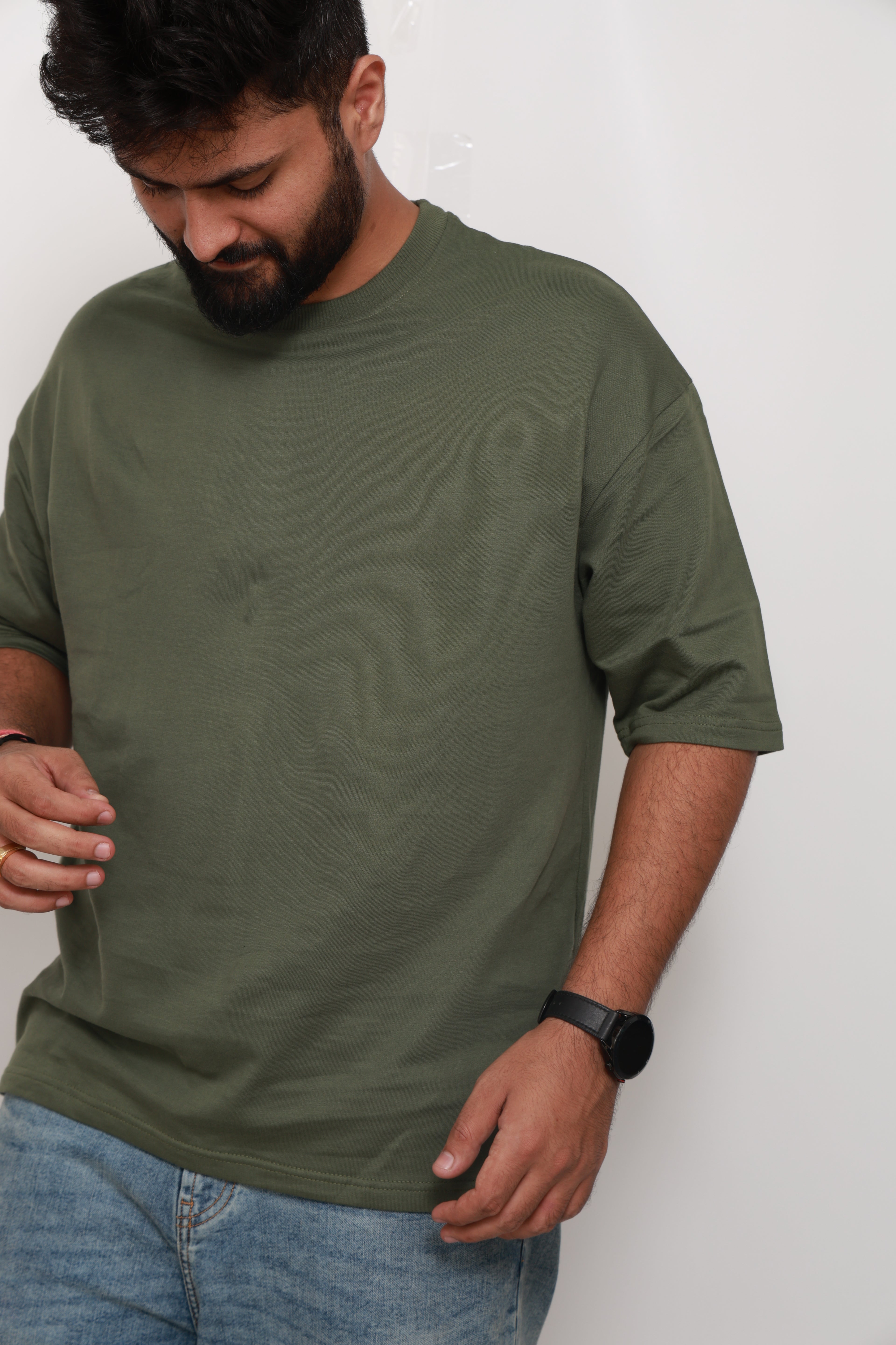 Man wearing a green shirt and blue jeans on a white background