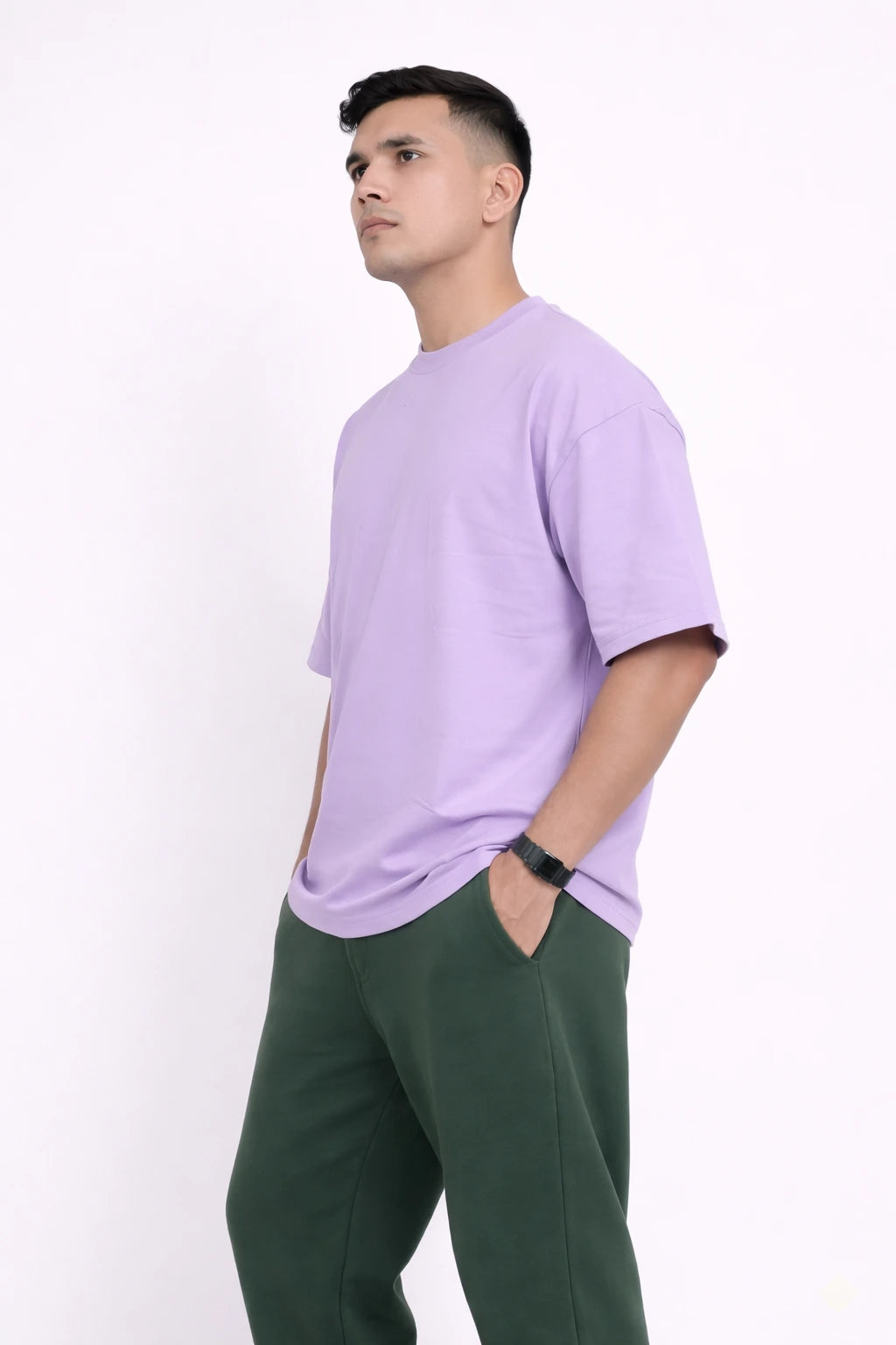 Man wearing a lavender t-shirt and green pants on a white background