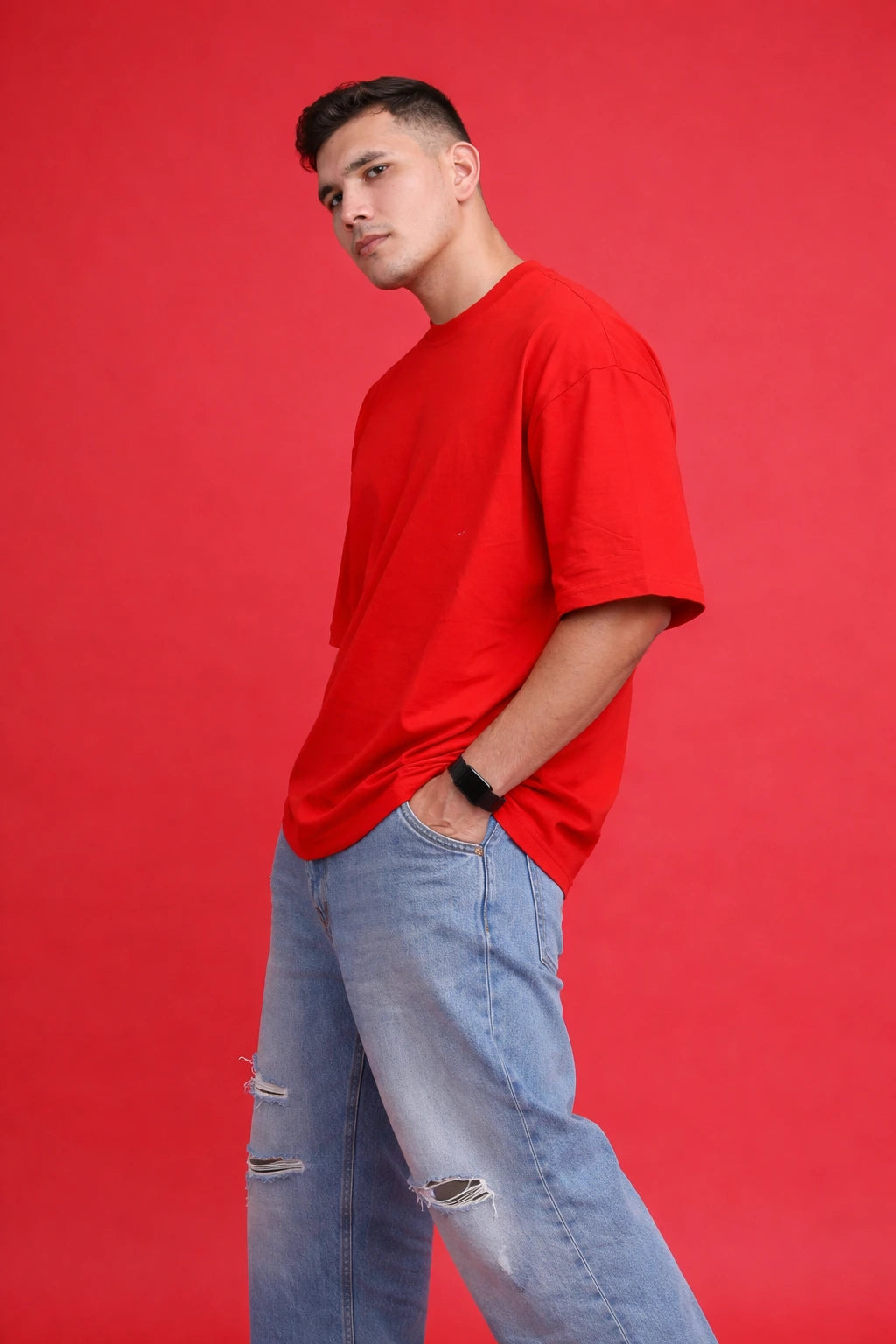 Man wearing a red t-shirt and light blue jeans against a red background