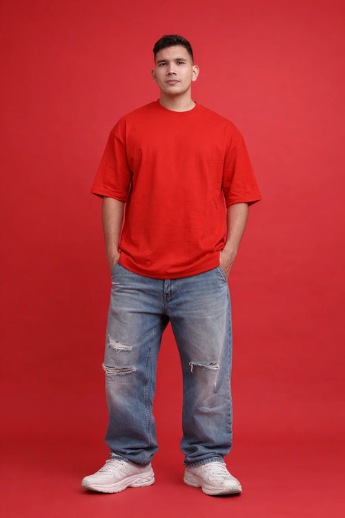 Person wearing a red t-shirt and blue jeans on a red background