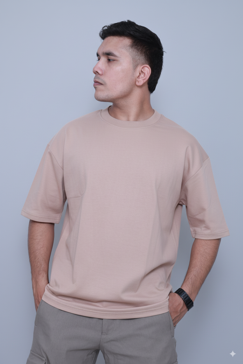 Man wearing a beige t-shirt and gray pants against a light blue background