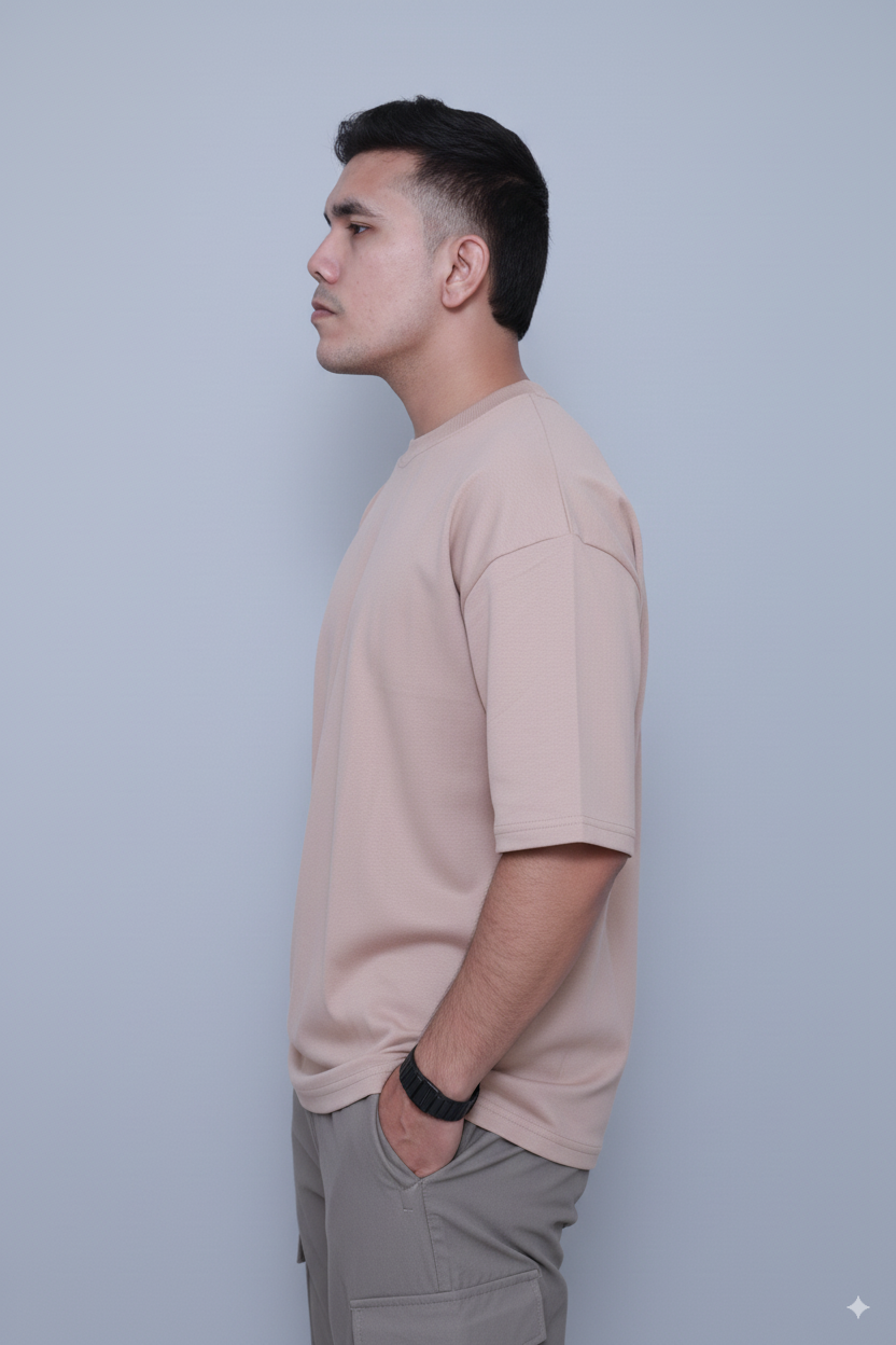 Man wearing a beige t-shirt and gray pants against a light blue background