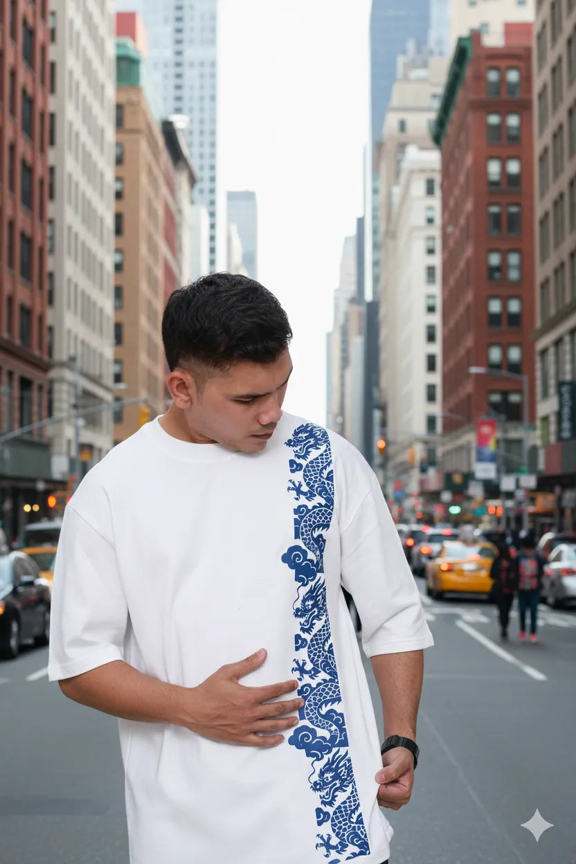 Man walking on a city street with a blue and white patterned oversized tshirt
