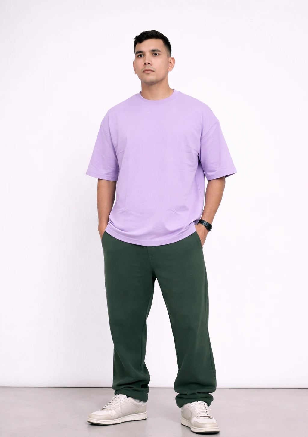 Man wearing a light purple t-shirt and green pants on a white background