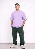 Man wearing a light purple t-shirt and green pants on a white background