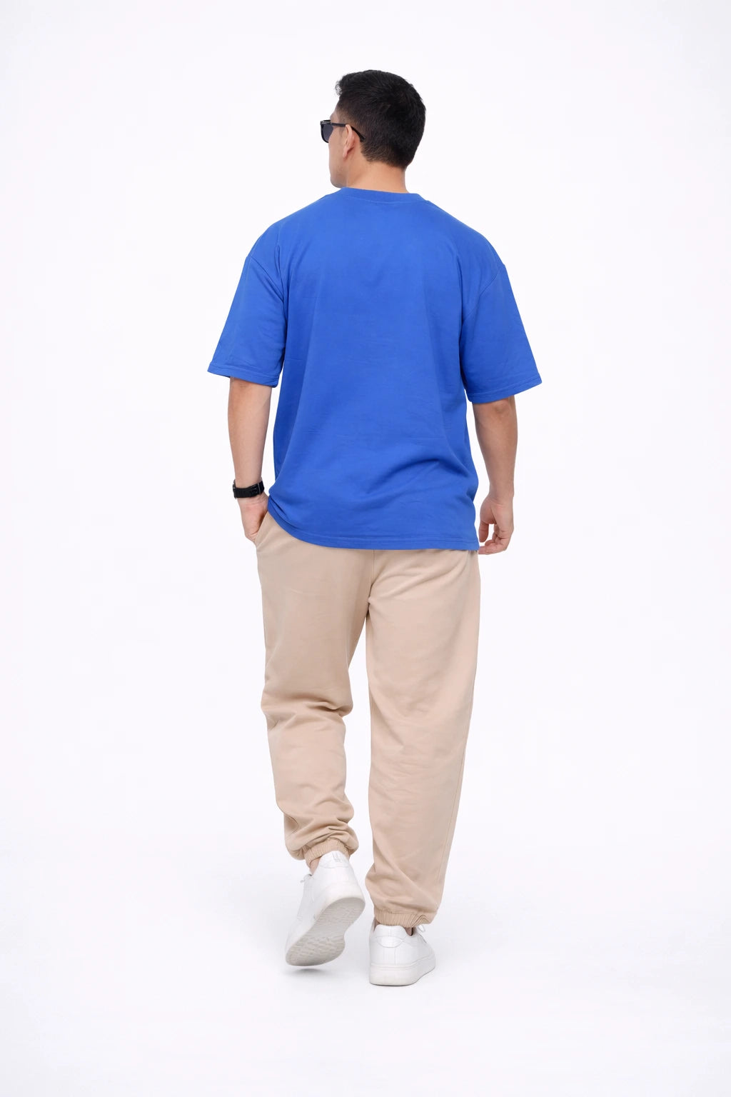 Man wearing a blue t-shirt and beige pants on a white background