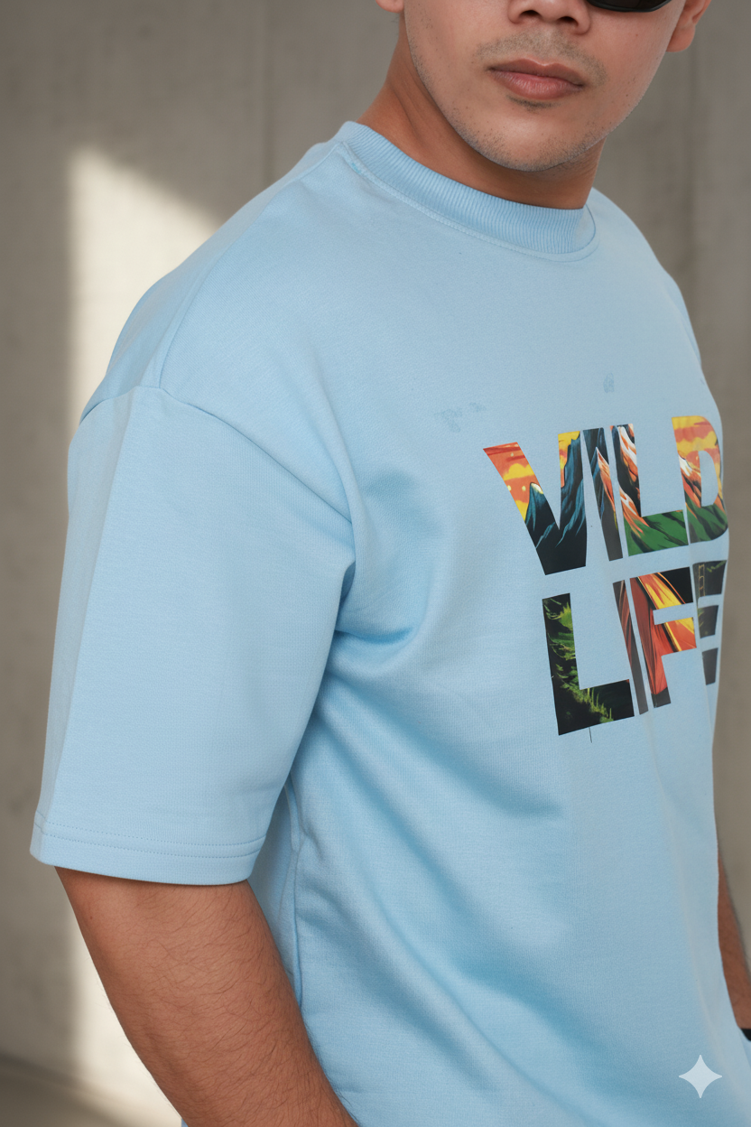 Person wearing a light blue t-shirt with colorful text design on a neutral background