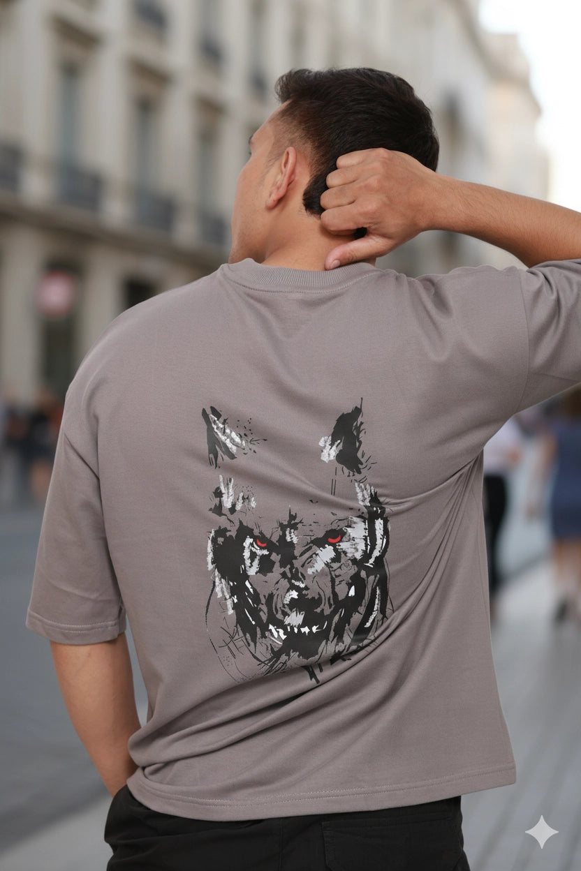 Man wearing a gray t-shirt with a black and white graphic design on the back, standing on a city street.