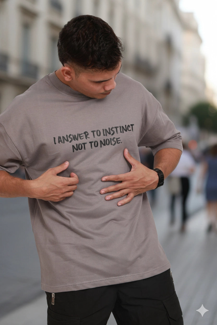 Man wearing a gray t-shirt with text on it, standing on a street.