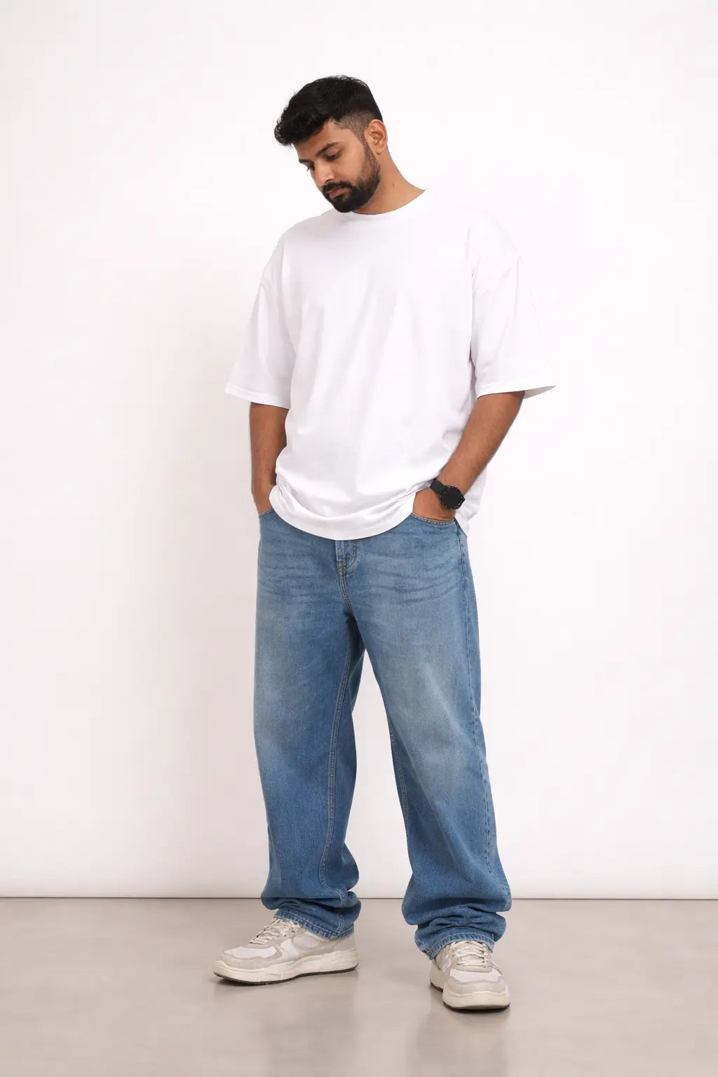 Man wearing a white t-shirt and blue jeans standing against a white background