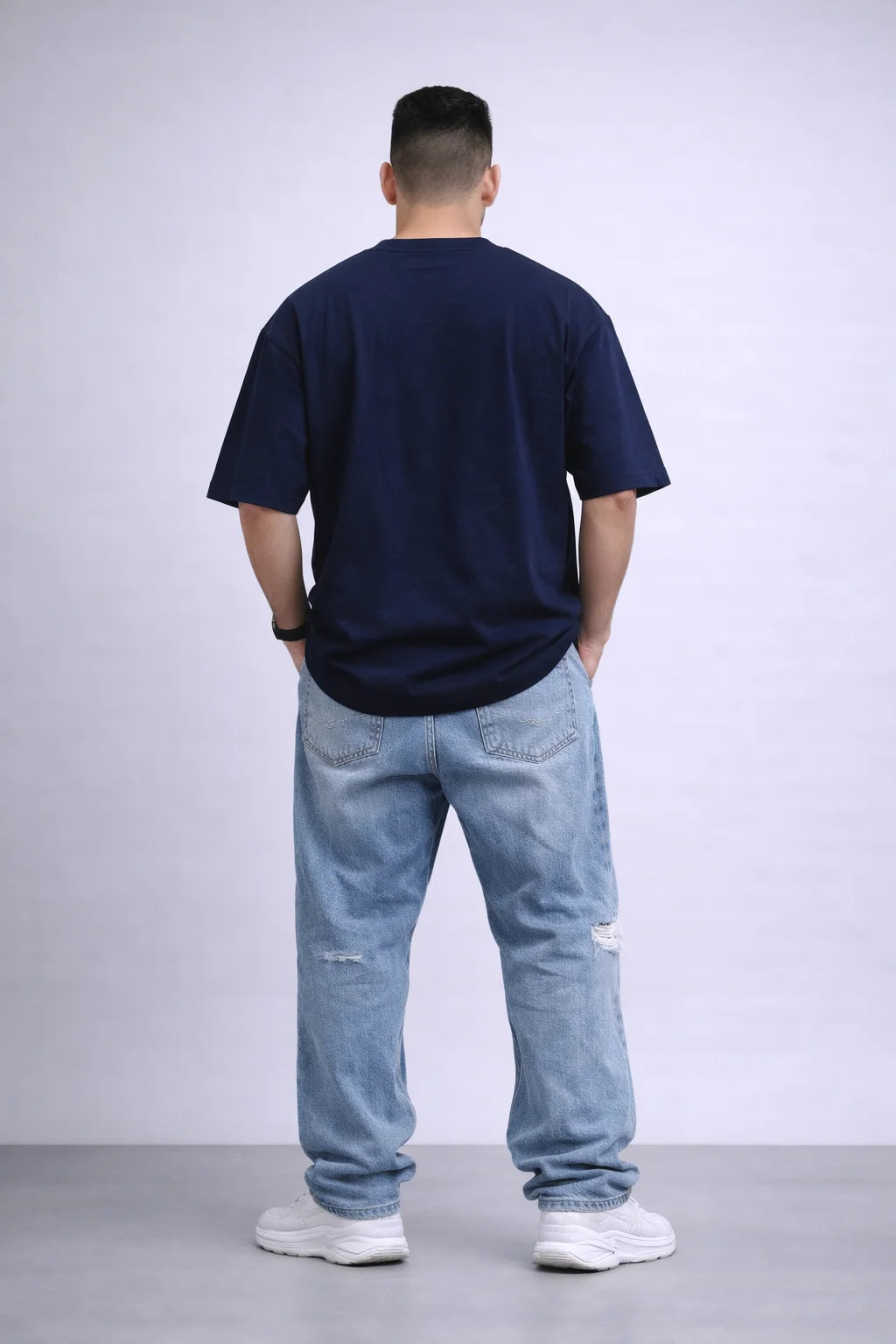 Person wearing a navy blue t-shirt and light blue jeans against a white background
