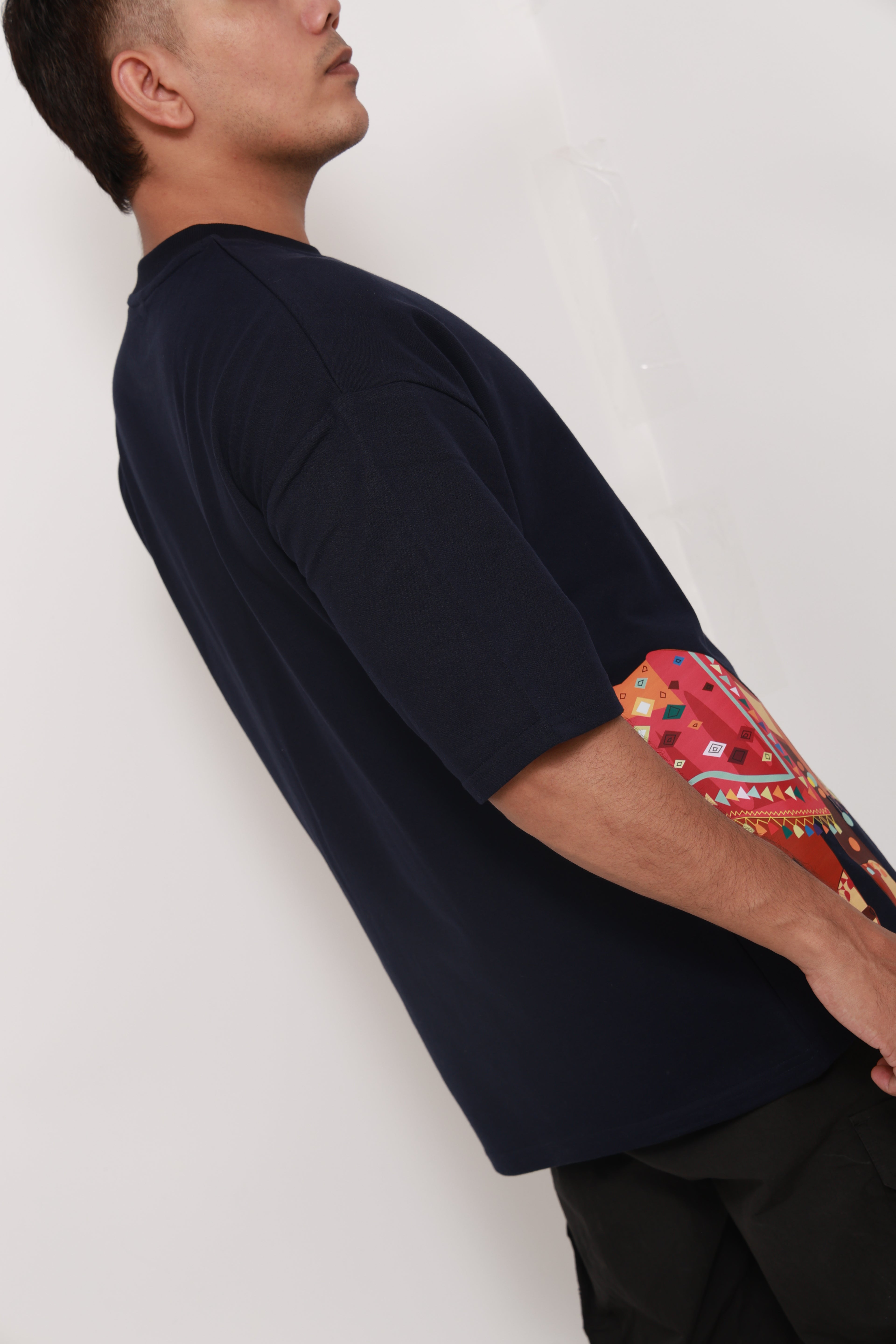 Person wearing a Navy BlueTshirt with a colorful graphic design of an artistic camel 