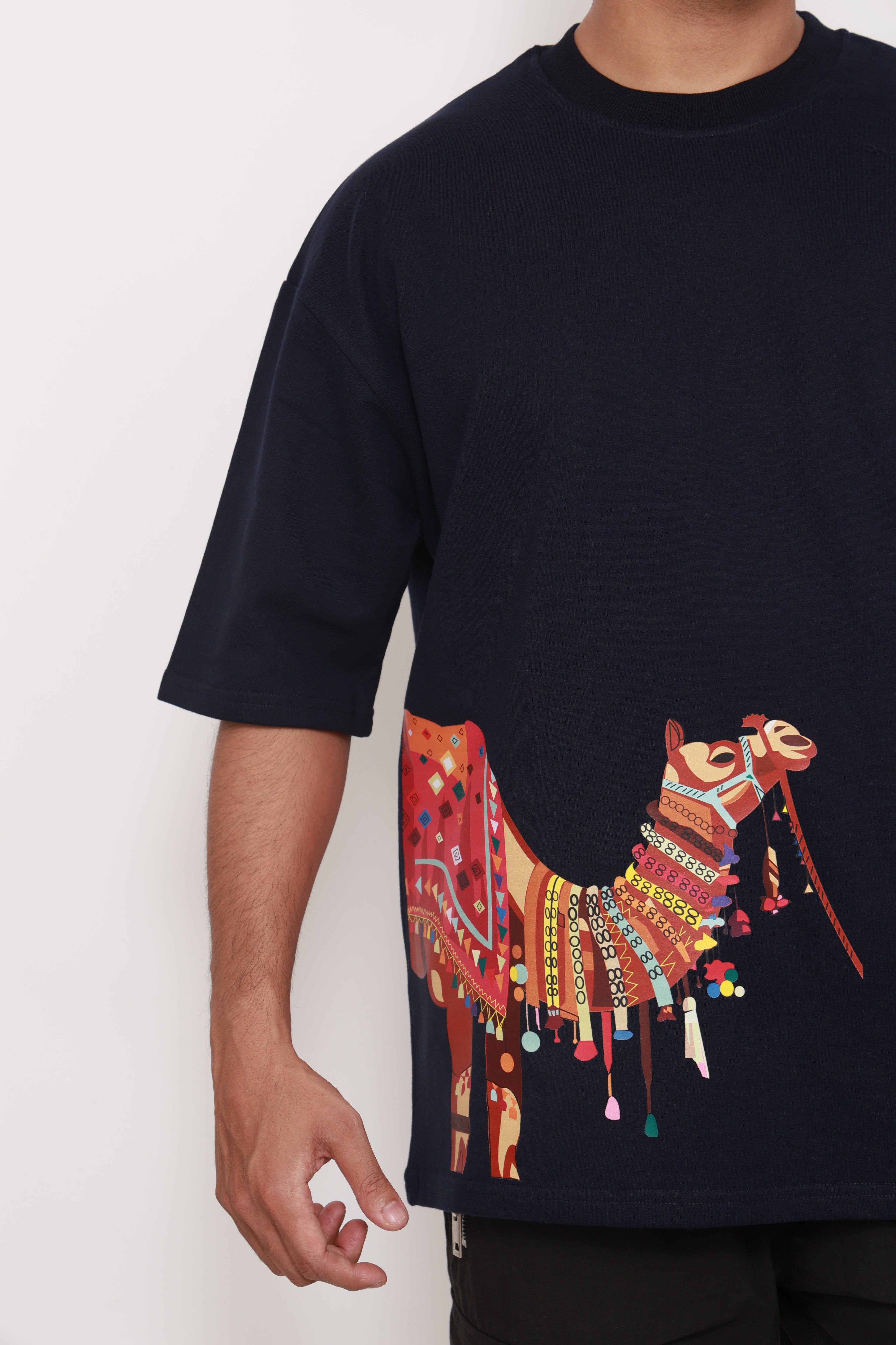 Person wearing a Navy BlueTshirt with a colorful graphic design of an artistic camel 
