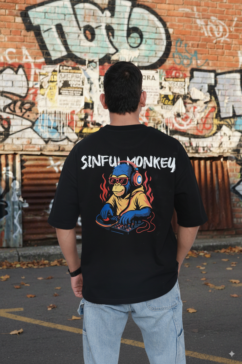 Person wearing a black t-shirt with 'Sinful Monkey' design in front of a graffiti-covered wall.