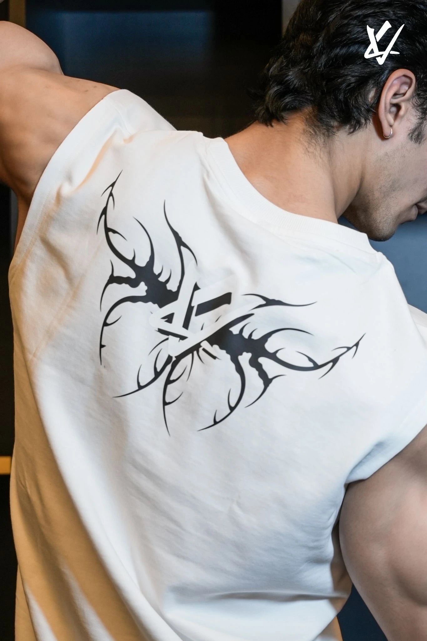 Person wearing a white t-shirt with a black tribal design on the back.