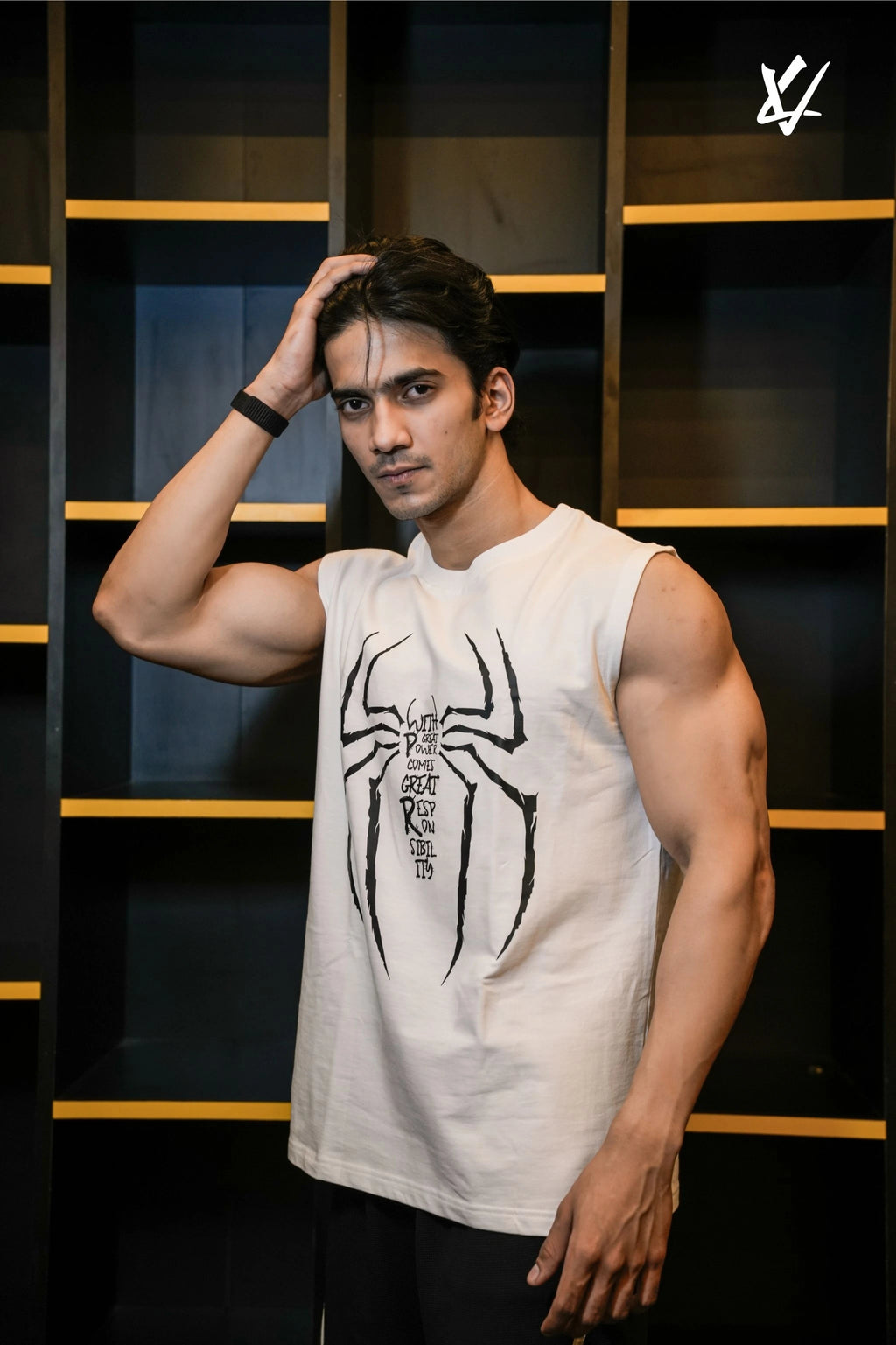 Man wearing a white sleeveless shirt with a black spider design against a dark background
