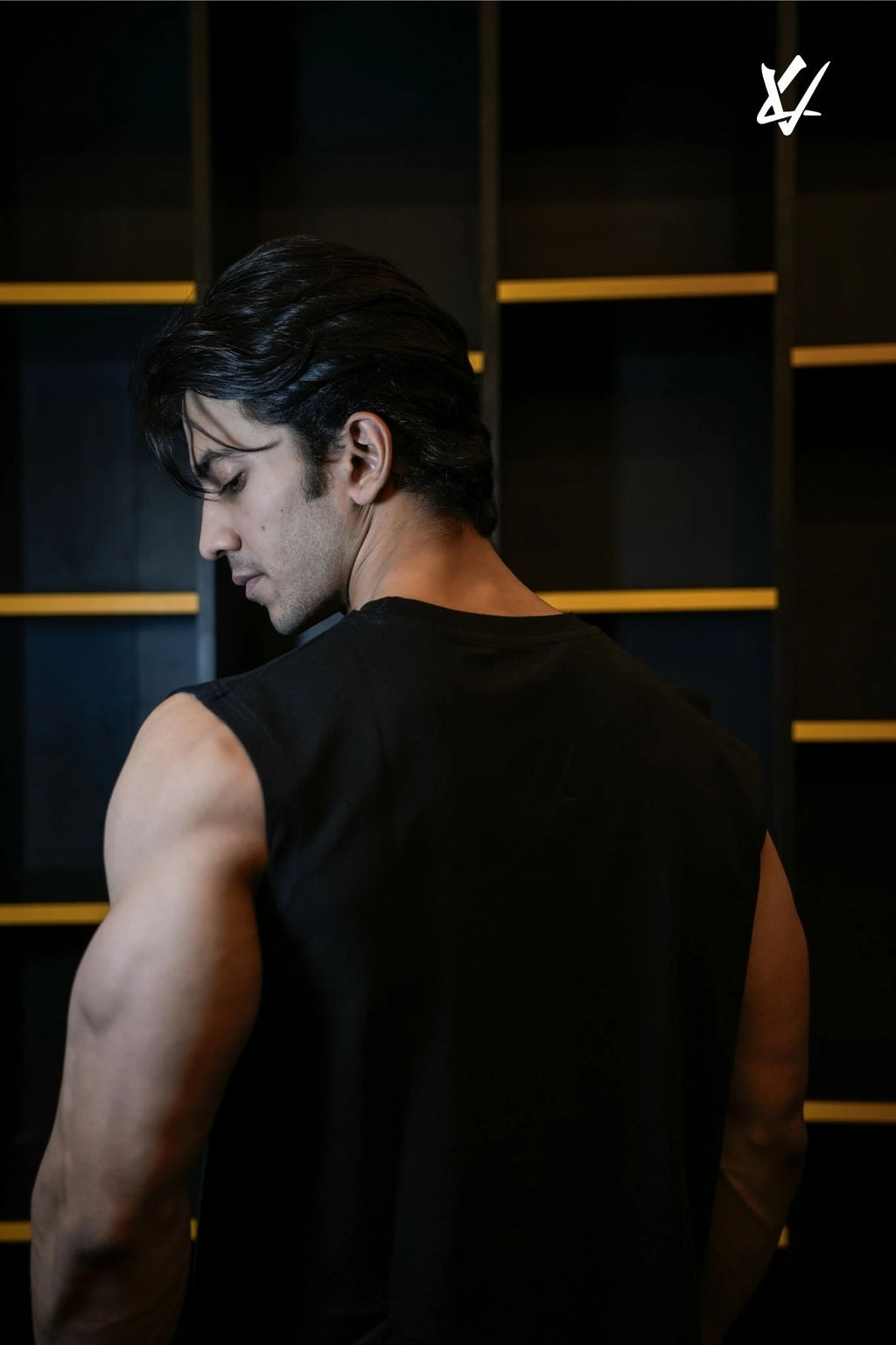 Man wearing a black sleeveless shirt against a dark background