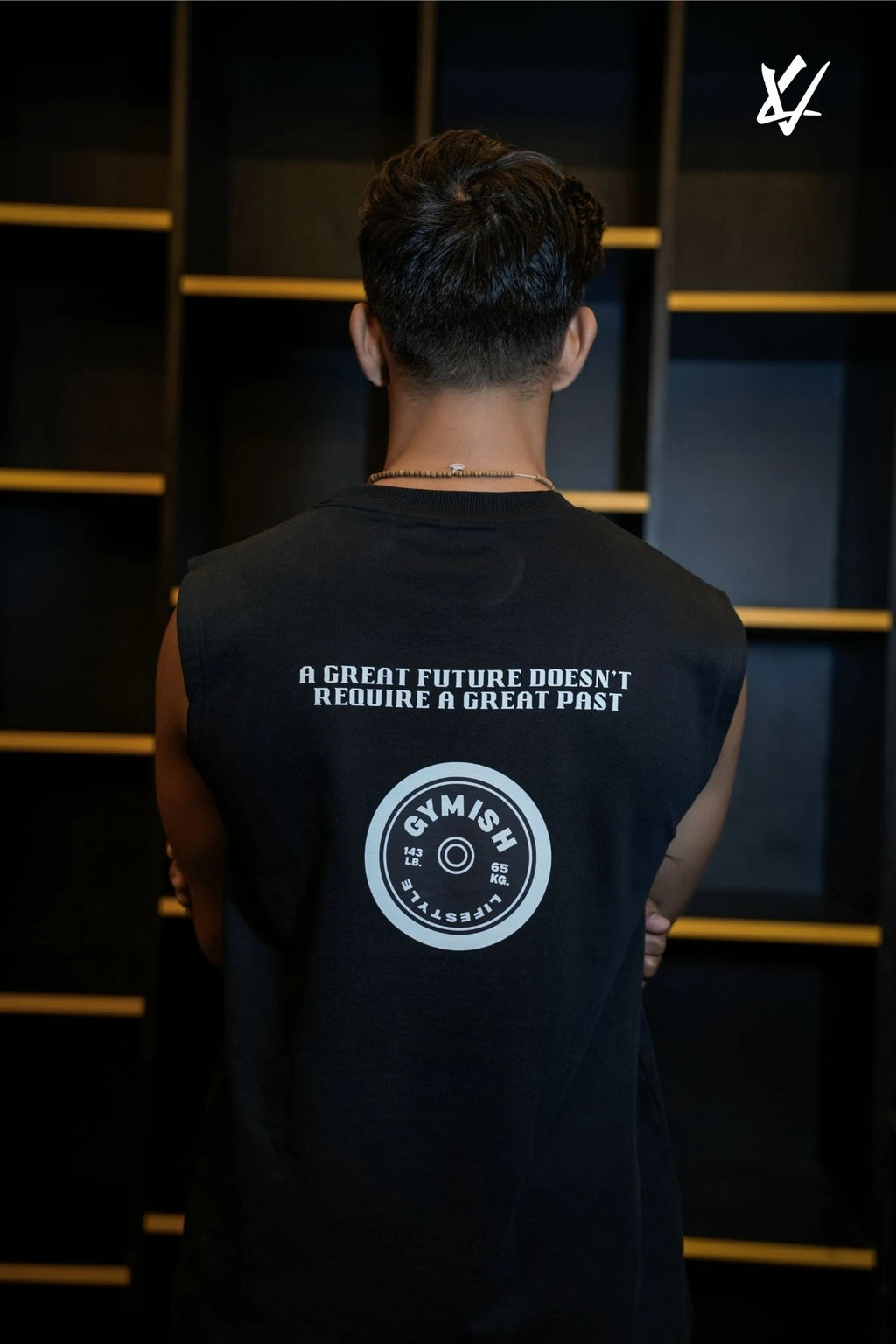 Person wearing a black sleeveless shirt with text and logo against a dark background