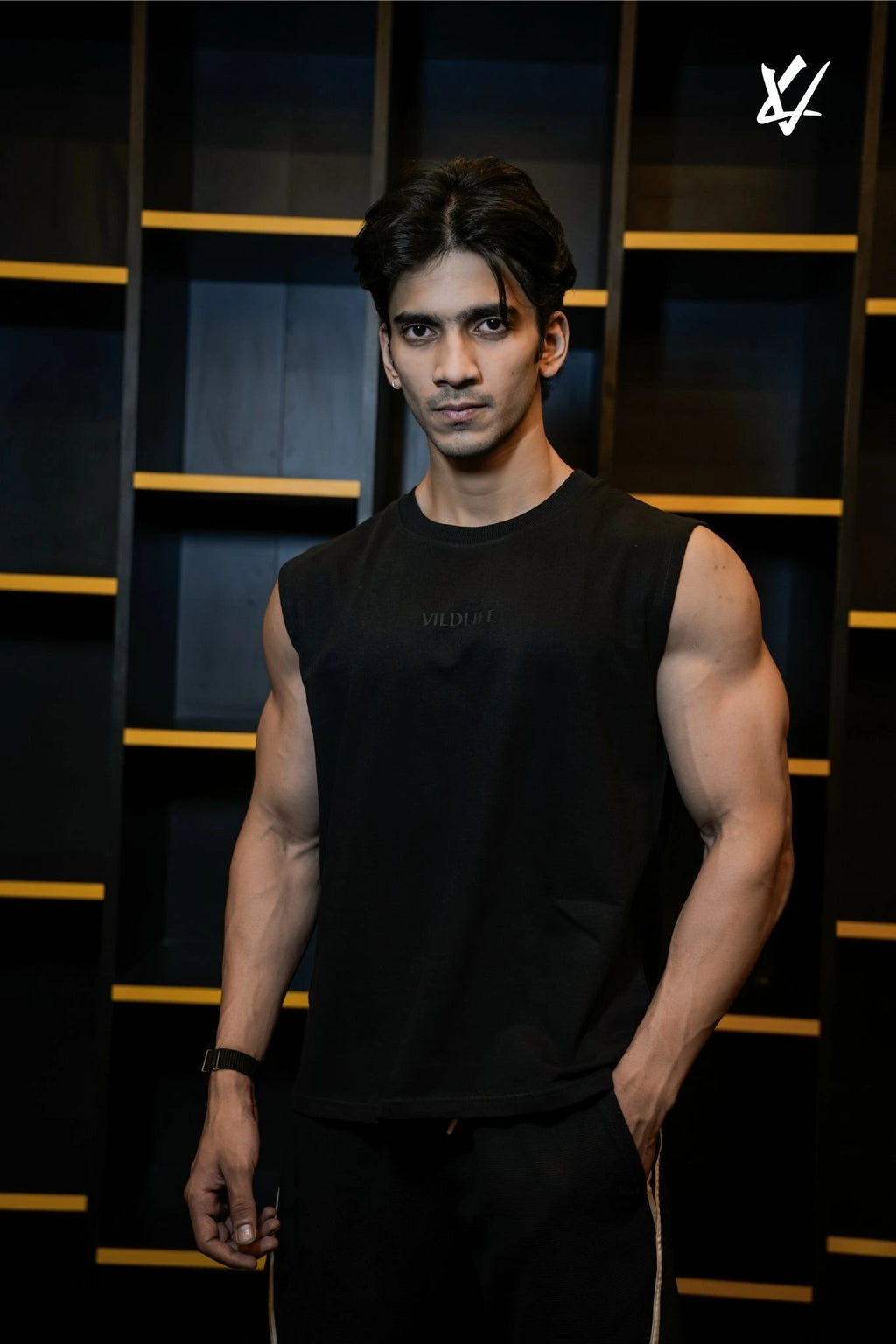Man wearing a black sleeveless shirt against a dark background