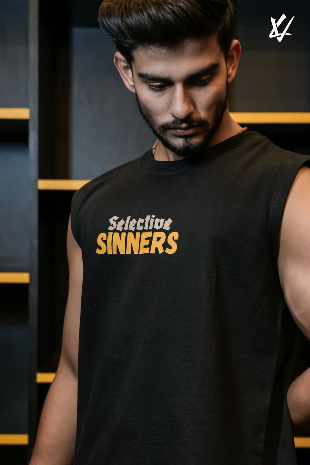 Man wearing a black sleeveless shirt with 'Selective Sinners' text in a dark setting