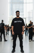 Man wearing a black t-shirt with text in a modern indoor setting